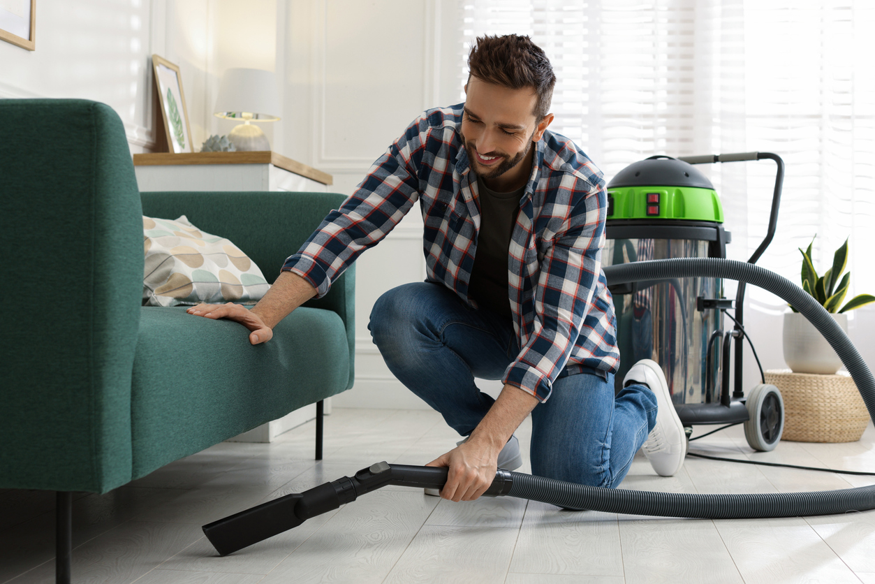 Homem passando aspirador na sua casa